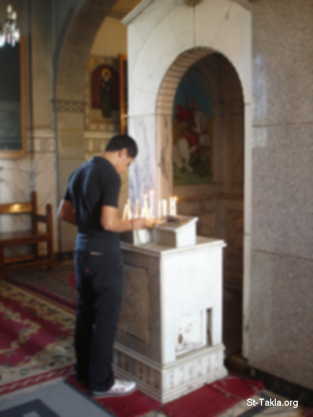 St-Takla.org Image: A young man praying and lighting candles in a Coptic Church - Photograph by Michael Ghaly for St-Takla.org     :         -    :   