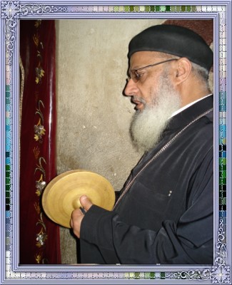 St-Takla.org Image: Rev. Father Hegomen Angelos Fathy Azer, pastor of St. TaklaHimanot Church in Alexandria, performing a praise ritual with a tambourine     :               
